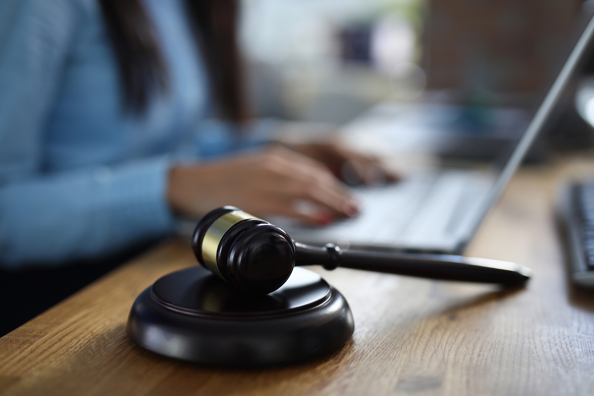Woman sits on table next to her lies wooden gavel for court hearings